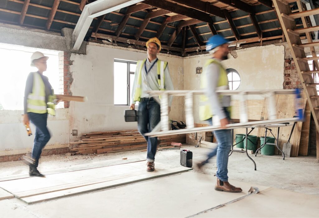 Construction crew carrying tools and materials inside a building renovation project in Chandler, AZ — the kind of cleanup made easier with a roll off dumpster rental.