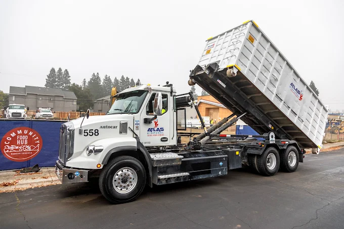 An Atlas Disposal truck with a roll off dumpster on it's way to deliver to a customer who used the Atlas Disposal tips. 
